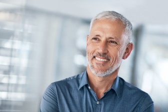 lächelnder Mann mit grauen Haaren und blauem Polo