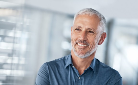 lächelnder Mann mit grauen Haaren und blauem Polo