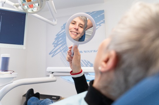Patientin schaut sich im Spiegel an | Zahnarztpraxis Kamberci in Olpe